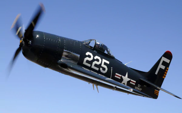 Grumman F8F Bearcat military aircraft (tail 225) banking in flight with spinning propeller against a clear blue sky — HD PC desktop wallpaper/background.