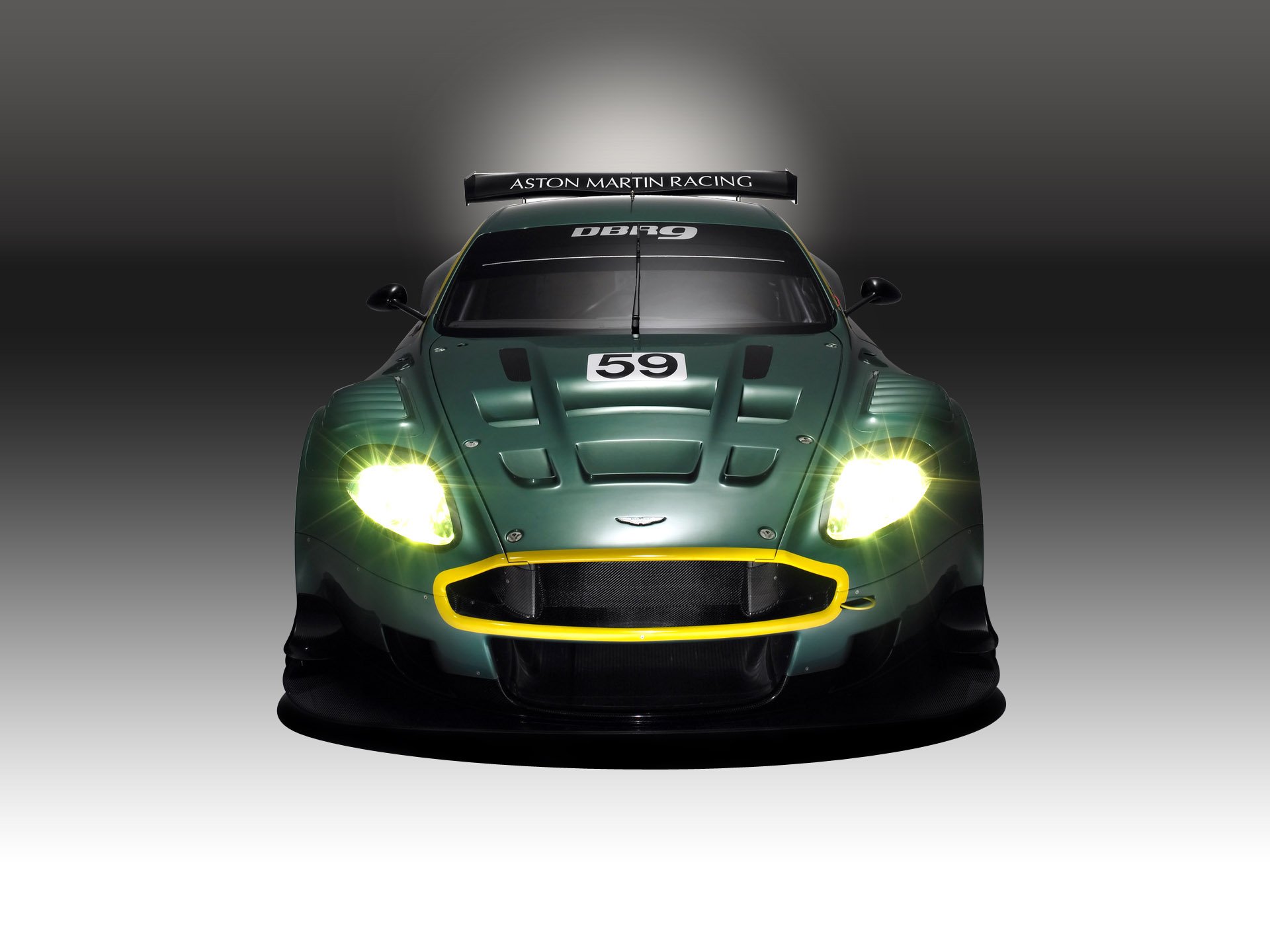 Front view of green Aston Martin DBR9 race vehicle with headlights ablaze and number 59, rendered as an HD PC desktop wallpaper and background.