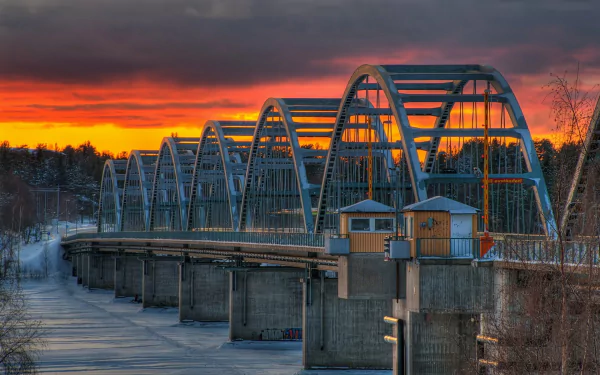 Sunset over Bergnäsbron, a man-made bridge in Sweden, casting warm hues across the sky and water in this HD desktop wallpaper.