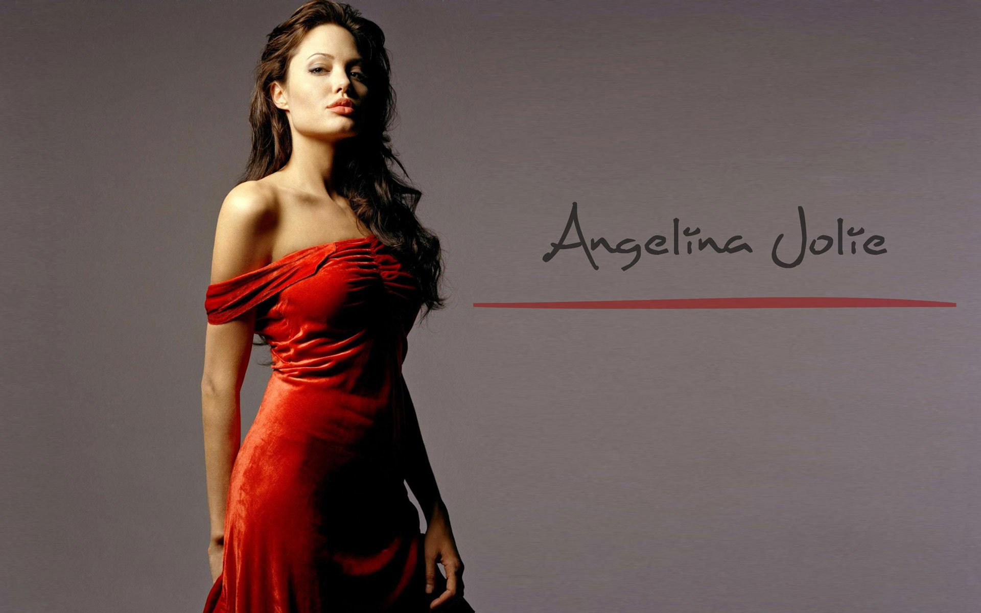 A stylish HD wallpaper of celebrity Angelina Jolie, featured in a striking red dress against a neutral background, showcasing her elegance and poise.
