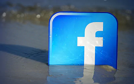 A vibrant HD wallpaper featuring the Facebook logo partially submerged in water, blending technology with a serene natural setting.