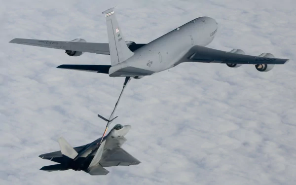 A Lockheed Martin F-22 Raptor refuels mid-air from a Boeing KC-135 Stratotanker above a cloud-covered landscape, shown in HD desktop wallpaper quality.