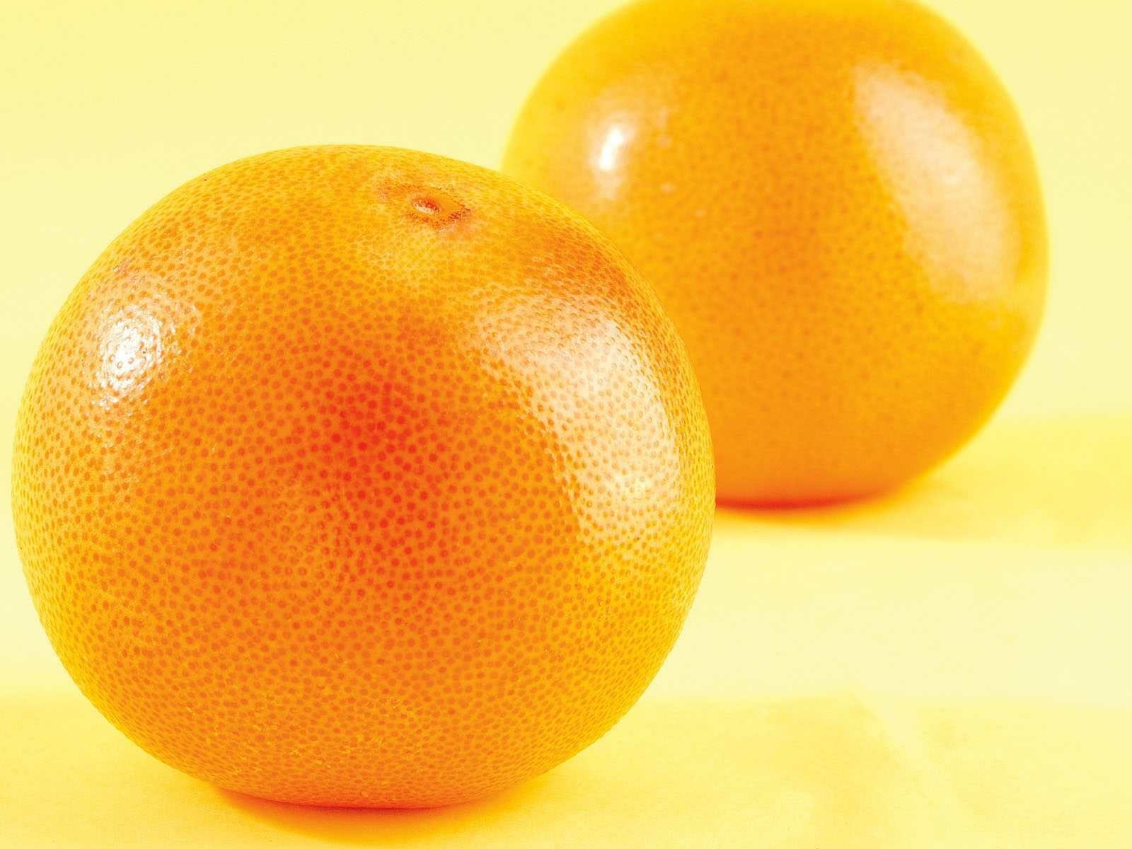 HD PC desktop wallpaper background showing two vibrant orange fruits on an orange-yellow backdrop, close-up textured peel, bright food-themed image.