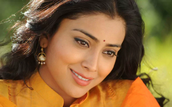 Brunette Bollywood actress Shriya Saran smiles warmly, adorned in traditional attire, presented as a vibrant 4K Ultra HD wallpaper for desktop backgrounds.
