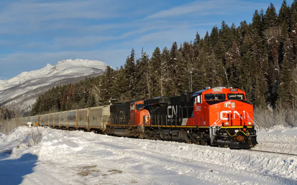 HD desktop wallpaper featuring a train moving through a snowy landscape with forested mountains in the background.