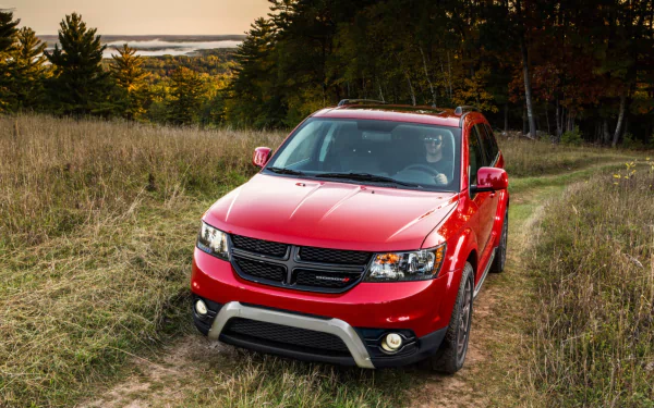 Red Dodge Journey parked on a grassy trail surrounded by trees under a clear sky, captured in a high-definition PC desktop wallpaper and background.