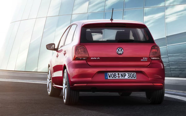 Rear view of a red Volkswagen Polo on a city street beside a reflective glass facade — HD PC desktop wallpaper and background.