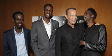 HD wallpaper featuring three men, one of whom resembles Tom Hanks, smiling at an event related to Captain Phillips.