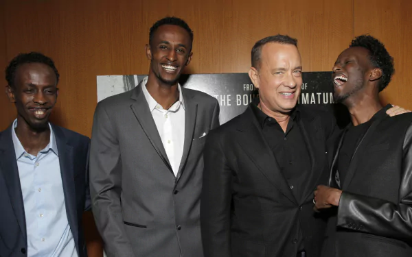 HD wallpaper featuring three men, one of whom resembles Tom Hanks, smiling at an event related to Captain Phillips.
