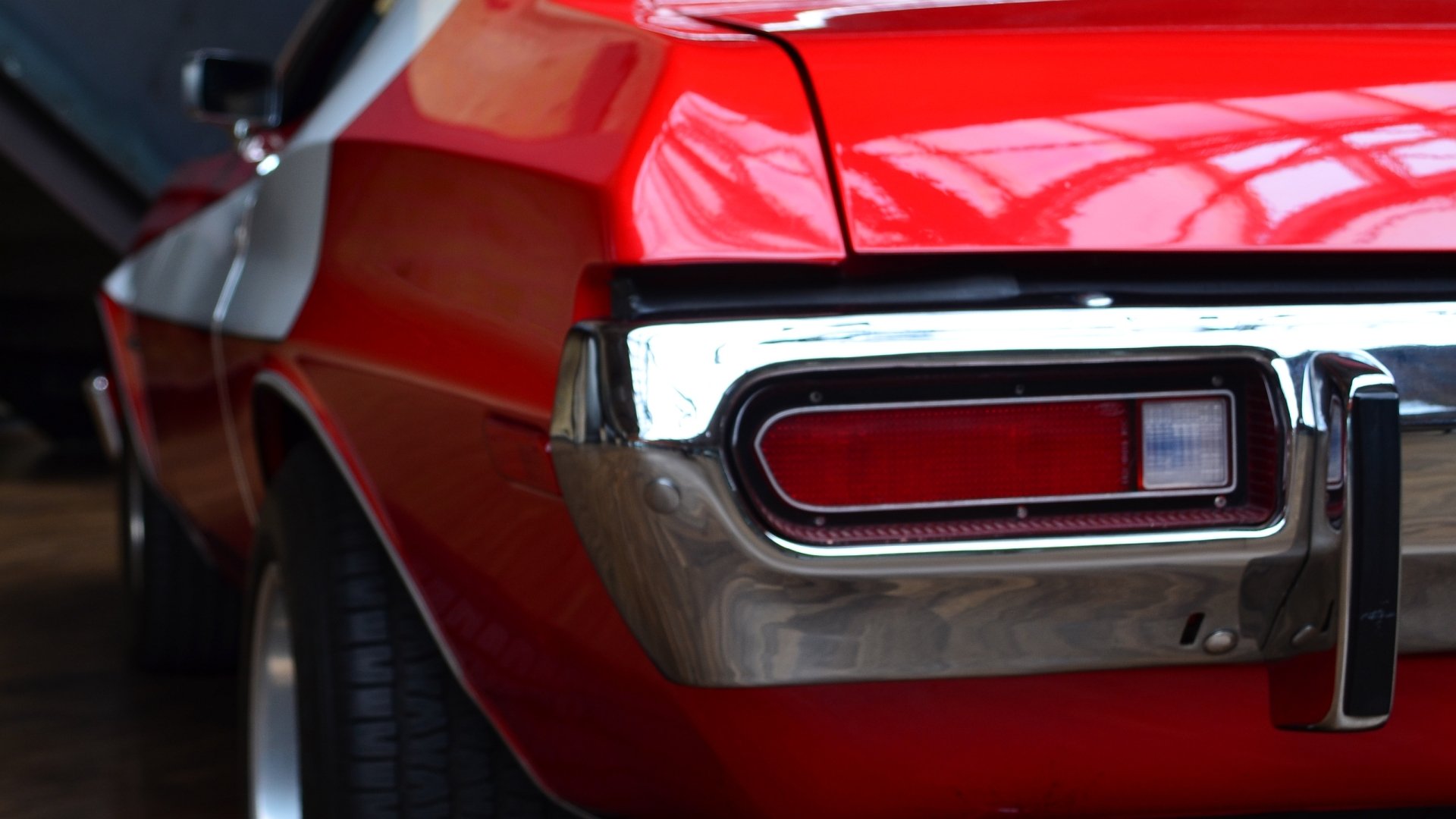 Close-up HD desktop wallpaper of a red Ford Gran Torino’s rear side, highlighting its taillight and chrome bumper with glossy reflections.