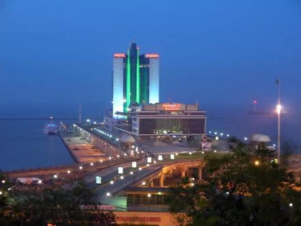 Night view of a man-made port area in Odessa with illuminated buildings and a pier extending into calm waters, featured as an HD PC desktop wallpaper.