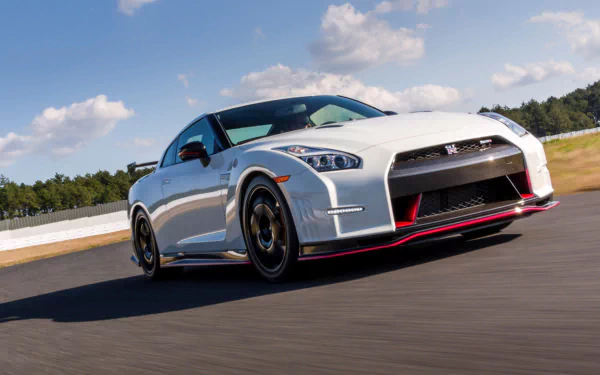 White Nissan GT-R Nismo vehicle speeding on a racetrack, low-angle dynamic shot — HD PC desktop wallpaper and background