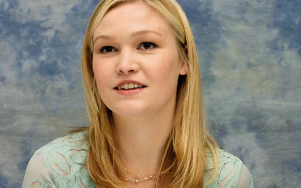 A close-up of celebrity Julia Stiles, showcasing her blonde hair and soft smile against a blue textured background, captured in HD for a desktop wallpaper.