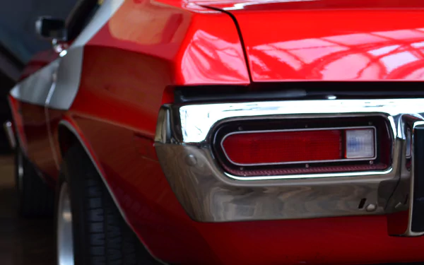 Close-up HD desktop wallpaper of a red Ford Gran Torino’s rear side, highlighting its taillight and chrome bumper with glossy reflections.