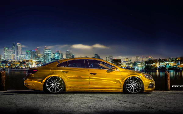 A sleek gold Volkswagen CC parked by a waterfront with a city skyline at night, captured in stunning 4K Ultra HD for PC desktop wallpaper and background.