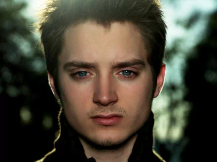 HD wallpaper featuring a close-up of a man with blue eyes and a subtle backdrop of trees, providing a serene background for desktops.