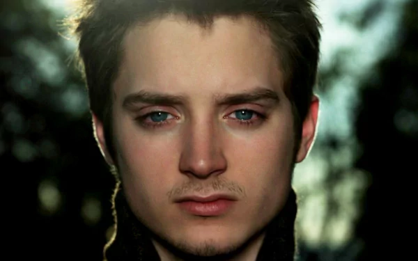 HD wallpaper featuring a close-up of a man with blue eyes and a subtle backdrop of trees, providing a serene background for desktops.