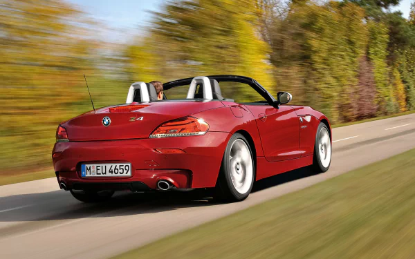Red BMW Z4 convertible driving past blurred autumn trees with motion blur — an HD PC desktop wallpaper and background featuring a BMW vehicle.