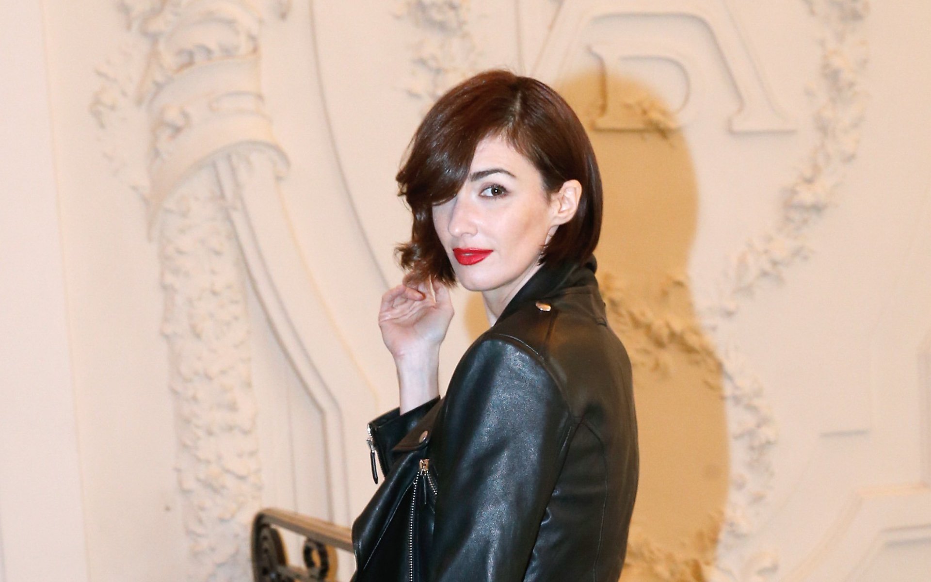 HD desktop wallpaper featuring Spanish actress and celebrity Paz Vega in a stylish black leather jacket against an elegant, ornate background.