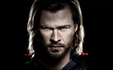 A striking HD wallpaper of Chris Hemsworth as Thor, showcasing the Australian actor's intense expression and iconic look against a dark background.
