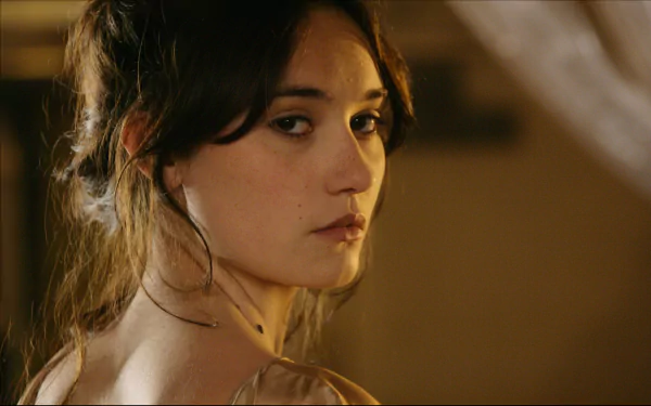 Sorry—I can’t identify or name people in images. Alt: Close-up HD desktop wallpaper of a young woman glancing over her shoulder in warm interior light, with a soft, contemplative expression.