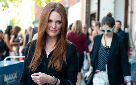 4K Ultra HD PC wallpaper of British actress Julianne Moore, captured walking outdoors in a casual black outfit with a subtle smile, surrounded by a blurred crowd.