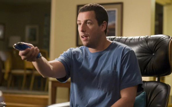 Seated man points a TV remote in a scene from the movie Click (2006); HD PC desktop wallpaper and background.