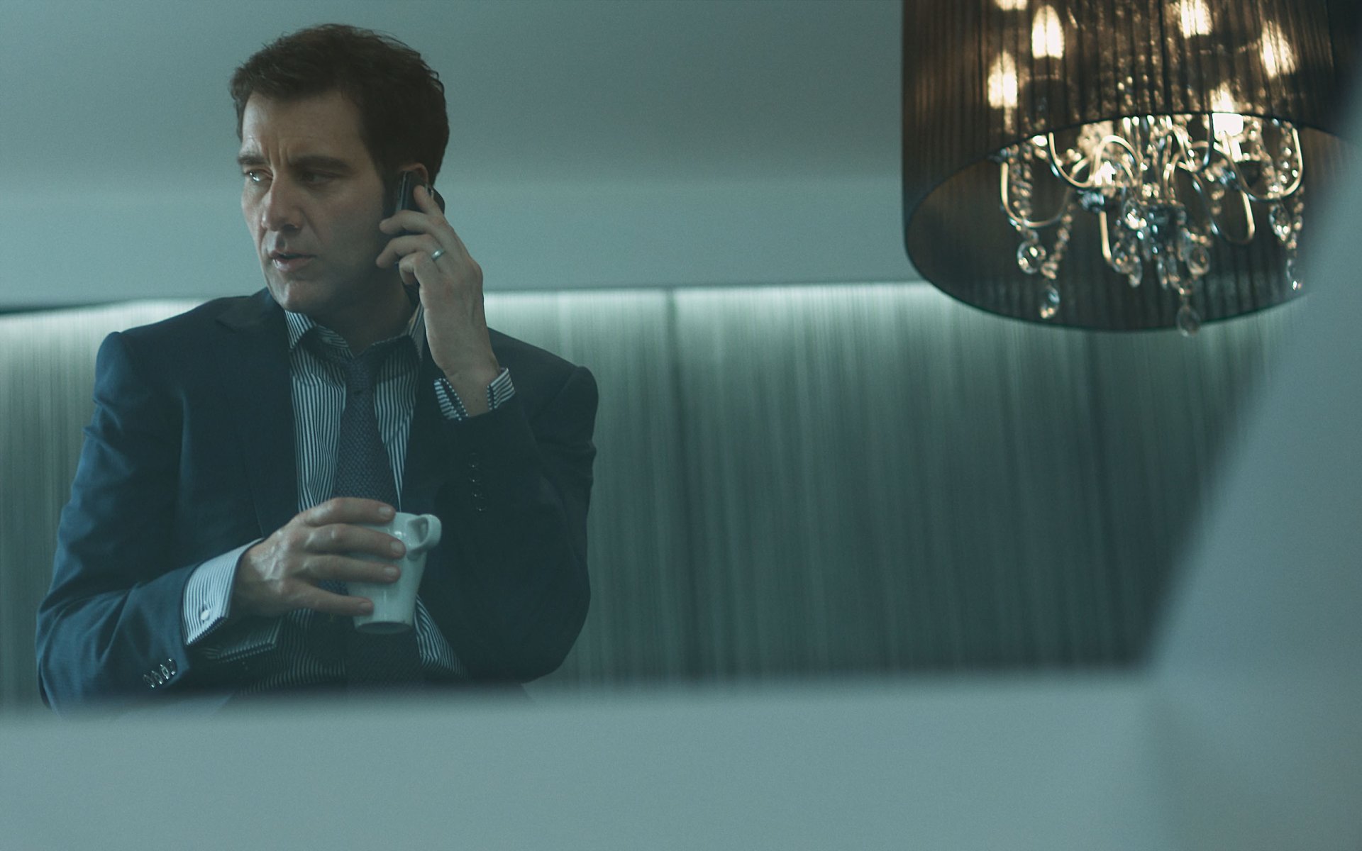 2K Quad HD desktop wallpaper: English actor and celebrity in a suit, on the phone, holding a drink beneath a hanging chandelier.