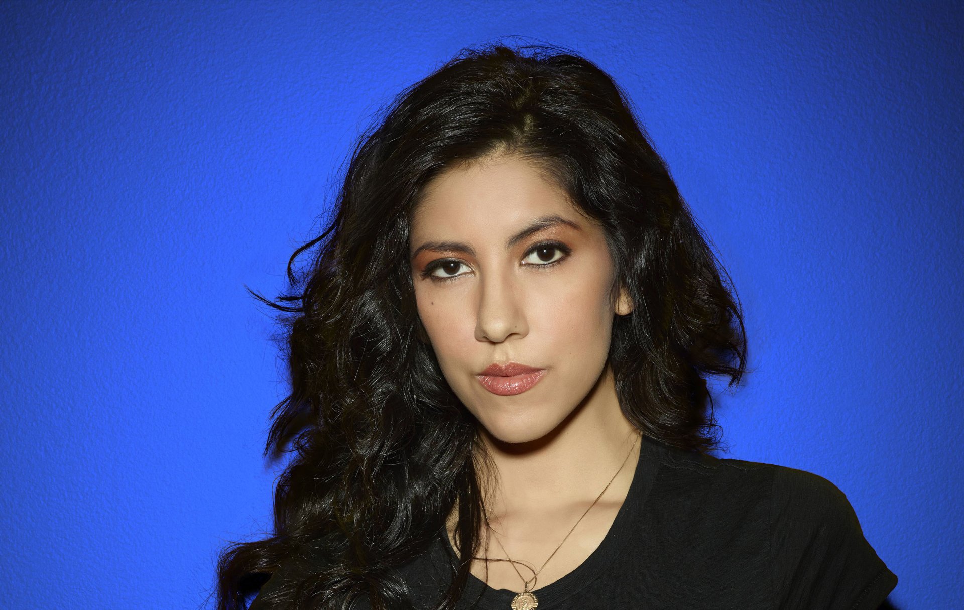 HD desktop wallpaper featuring a portrait of a woman against a blue background, tagged with Stephanie Beatriz.