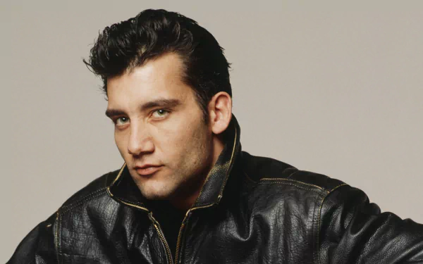 Close-up headshot of a man in a black leather jacket against a neutral backdrop, posed and lit for a 2K Quad HD PC desktop wallpaper.