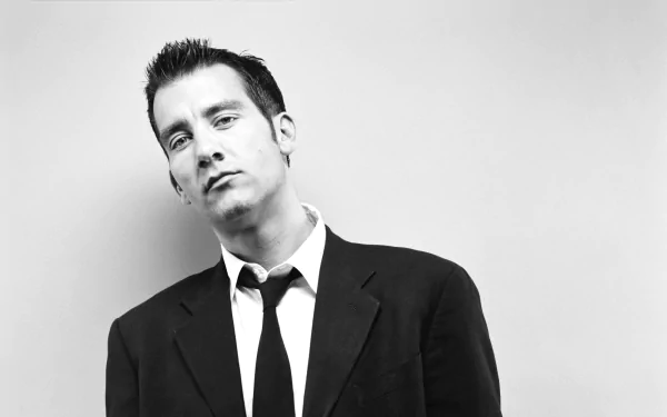 Black-and-white 2K Quad HD PC desktop wallpaper: portrait of an English actor in a suit with a loosened tie, gazing slightly off-camera.