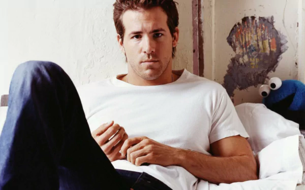 HD desktop wallpaper featuring a relaxed man sitting in bed, with neutral tones and a plush blue character in the background.