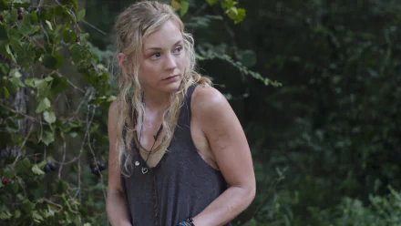 HD PC desktop wallpaper of a female survivor from The Walking Dead, sleeveless top, crouched at the woodland edge with a wary, alert expression.