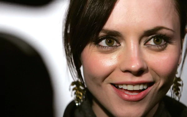 HD PC desktop wallpaper featuring a close-up of celebrity Christina Ricci smiling with dark hair and statement earrings.