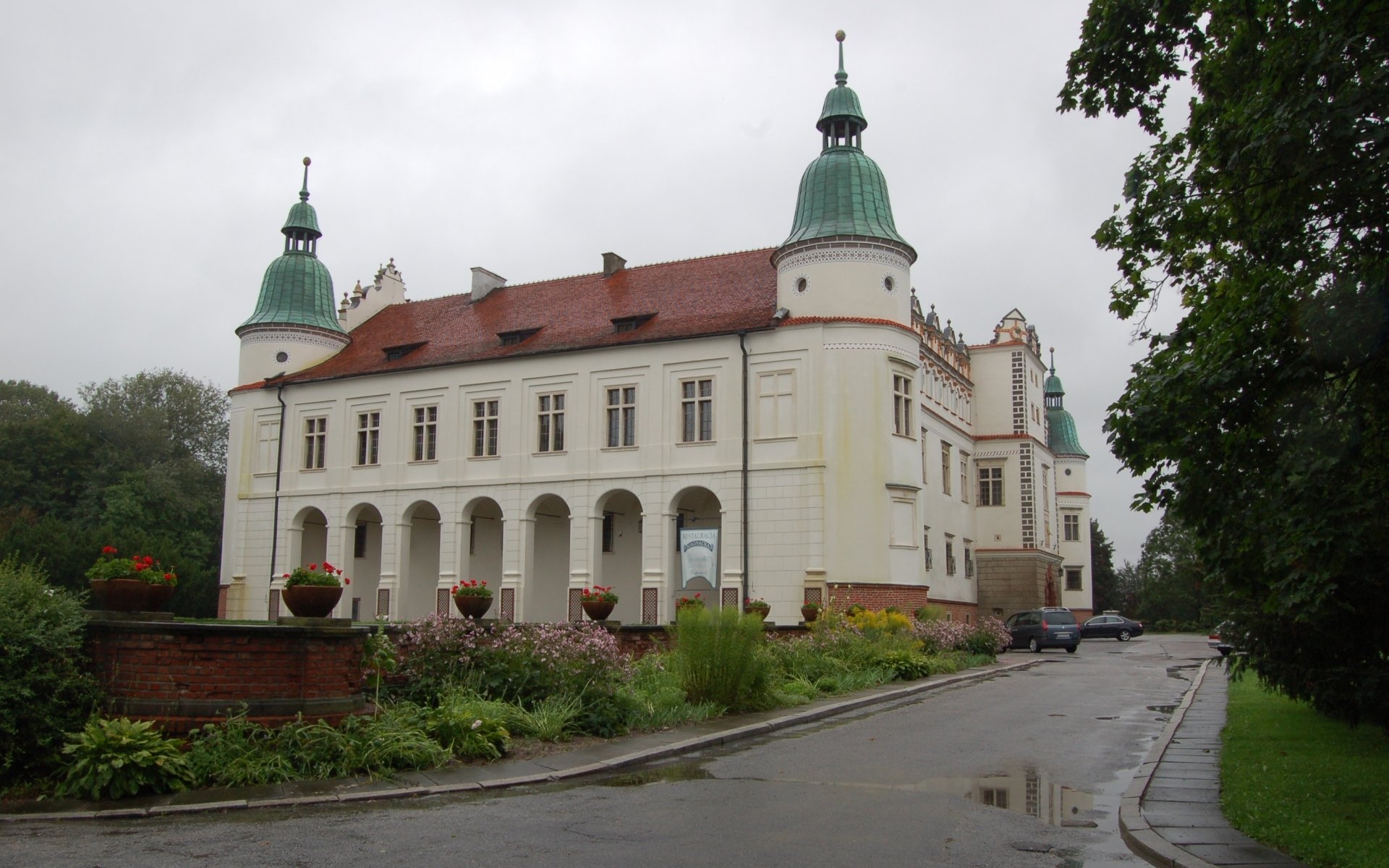 HD desktop wallpaper featuring the historic Baranów Sandomierski Castle, a man-made architectural landmark with distinctive towers and a red roof under a cloudy sky.