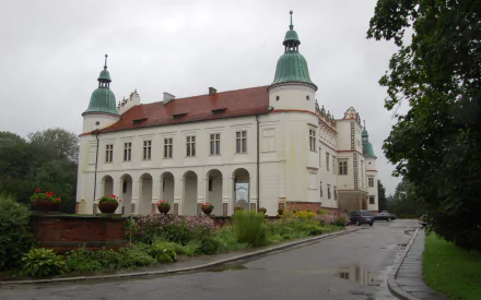 HD desktop wallpaper featuring the historic Baranów Sandomierski Castle, a man-made architectural landmark with distinctive towers and a red roof under a cloudy sky.