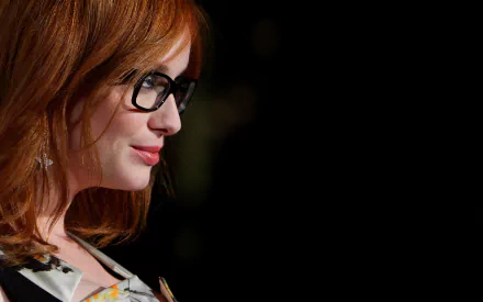 HD desktop wallpaper featuring American actress and celebrity Christina Hendricks in a close-up profile shot wearing glasses.