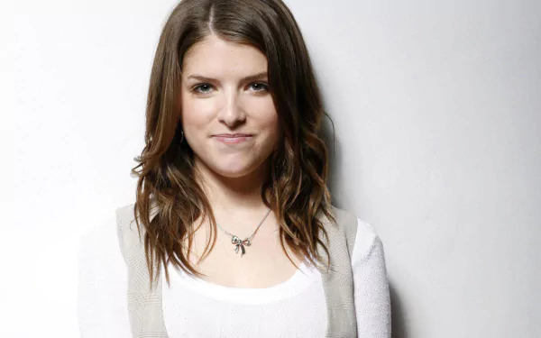 HD desktop wallpaper featuring American actress and celebrity Anna Kendrick against a plain light background, smiling softly with loose wavy hair.