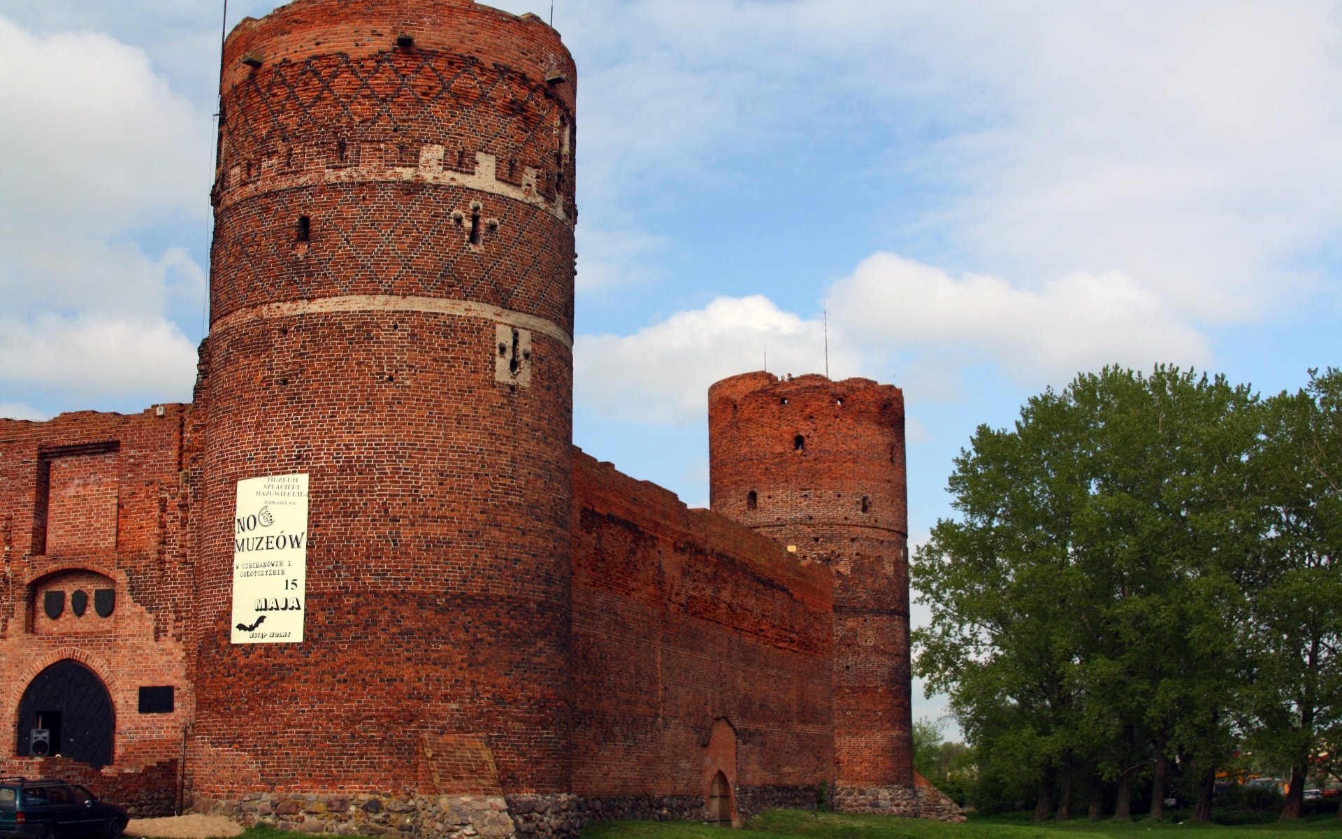HD PC desktop wallpaper/background: Ciechanów Castle — red-brick medieval towers and walls (man-made) beneath a blue sky with trees.
