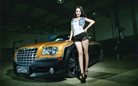 A confident woman poses beside a sleek orange car in a dimly lit garage, showcasing a stylish blend of automotive culture and fashion in this HD desktop wallpaper.