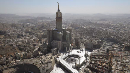 An aerial view of the Mecca Clock Tower, showcasing its impressive architecture against the sprawling landscape of Mecca. A stunning HD desktop wallpaper and background.