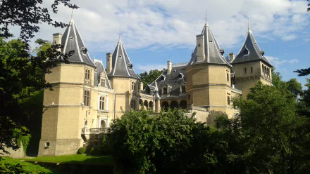Goluchów Castle: man-made historic chateau with turreted towers amid green trees under blue sky — 2K Quad HD PC desktop wallpaper/background.