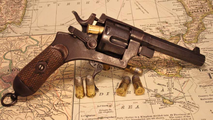 A vintage revolver rests on an antique map, surrounded by spent cartridges, capturing a sense of history and craftsmanship. High-definition desktop wallpaper for enthusiasts.