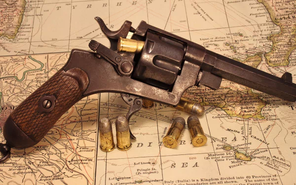 A vintage revolver rests on an antique map, surrounded by spent cartridges, capturing a sense of history and craftsmanship. High-definition desktop wallpaper for enthusiasts.
