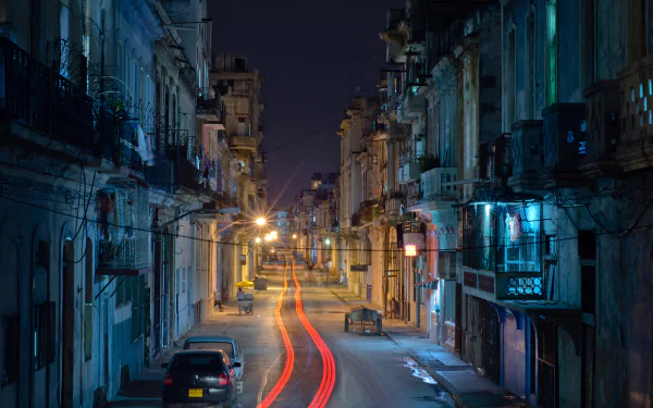 Man-made urban scene in Havana at night: narrow colonial street with balconies, parked cars and red light trails — HD PC desktop wallpaper/background.