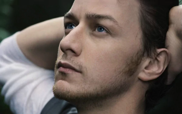 A close-up of Scottish actor James McAvoy, featuring his thoughtful expression and striking blue eyes, set against a blurred natural background. An HD desktop wallpaper.