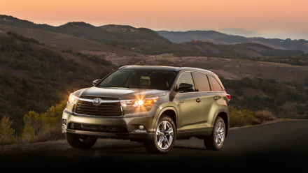 HD PC desktop wallpaper featuring a Toyota Highlander Hybrid vehicle parked on a scenic road with rolling hills under a soft sunset sky.