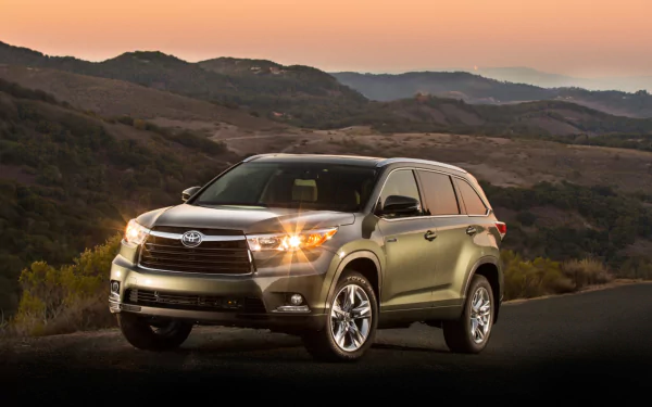 HD PC desktop wallpaper featuring a Toyota Highlander Hybrid vehicle parked on a scenic road with rolling hills under a soft sunset sky.