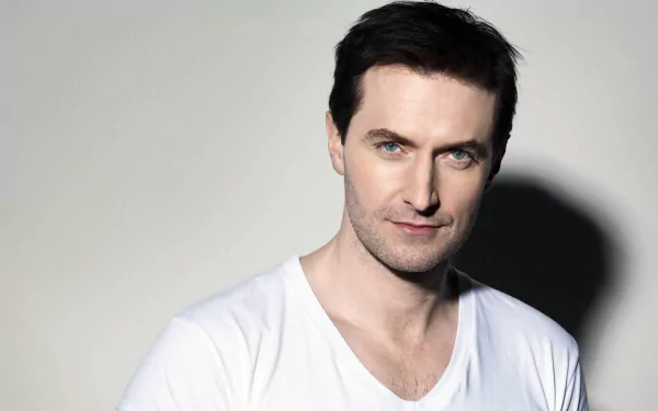 Close-up portrait of a dark-haired man in a white T-shirt against a soft gray background — 2K Quad HD PC desktop wallpaper.