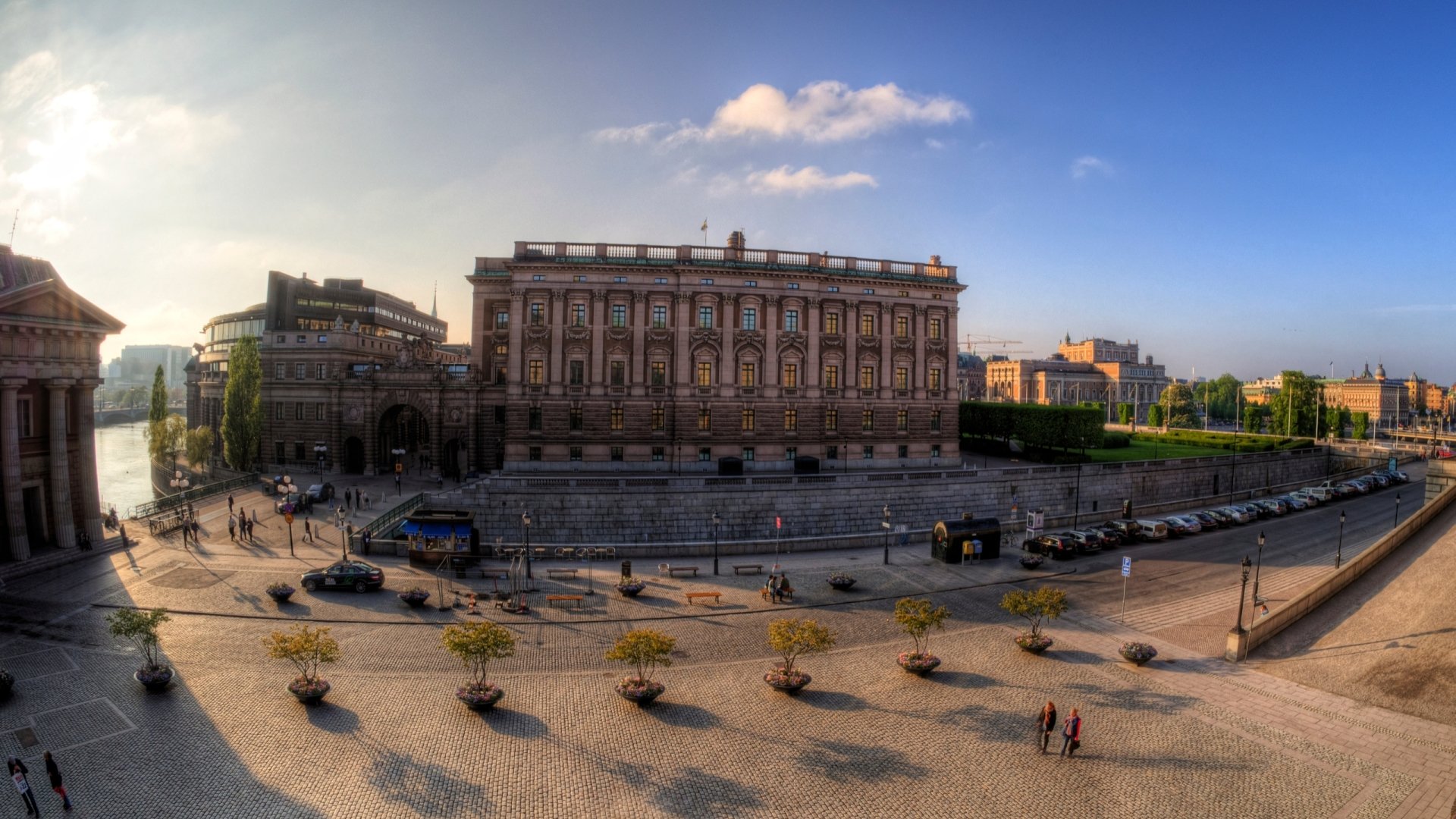 2K Quad HD PC desktop wallpaper: Stockholm, Sweden — man-made historic palace and sunlit waterfront square beneath a clear blue sky.